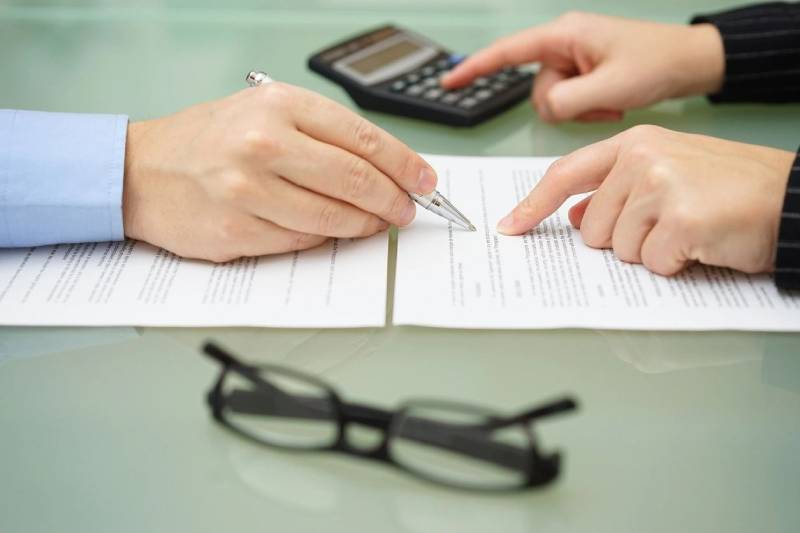 Two people are writing on a piece of paper.